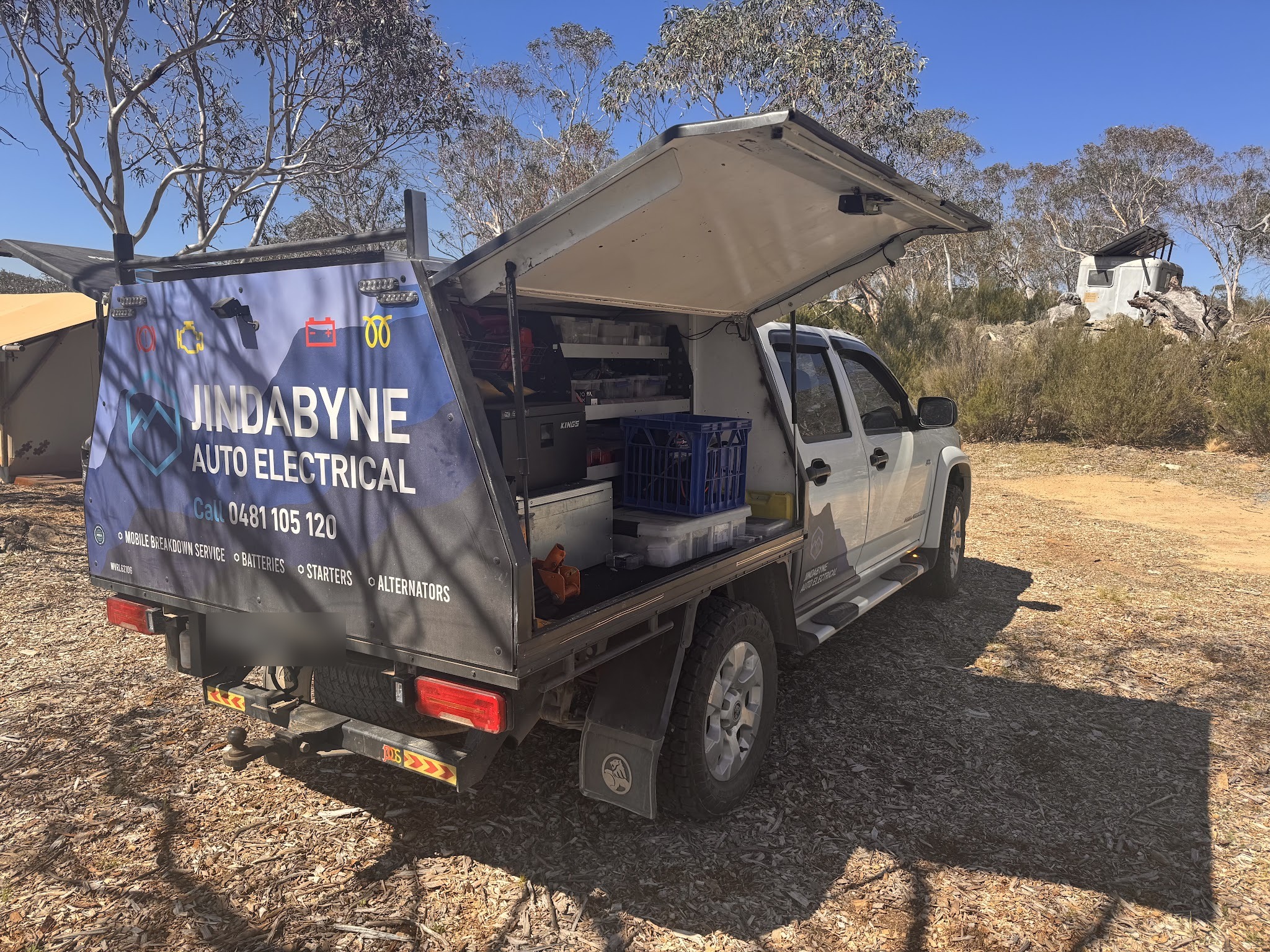 The work ute in the bush with its canopy lifted, showing the drawers, parts trays and tooling carried on board