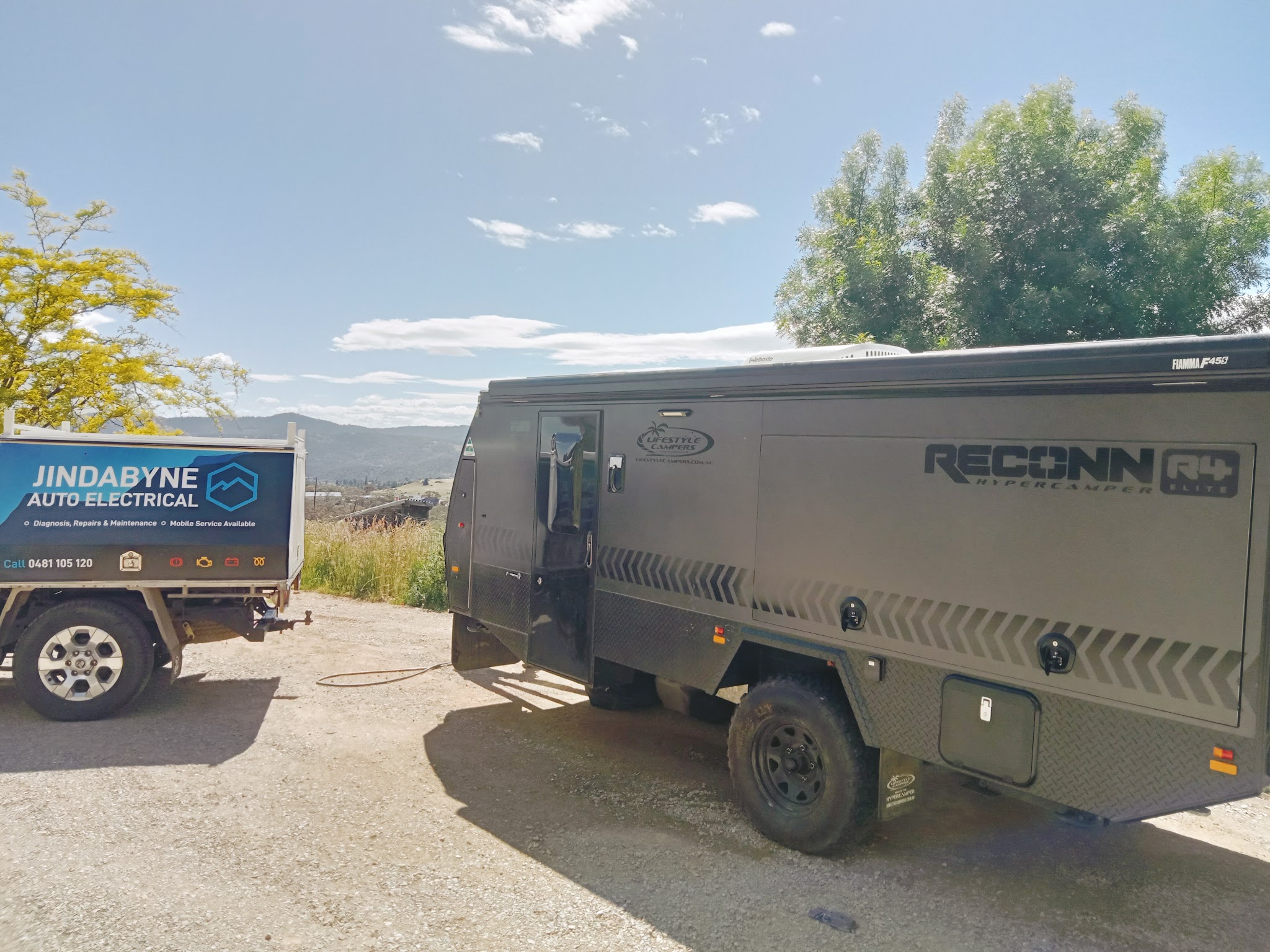 The Jindabyne Auto Electrical truck parked alongside an off road camper on a job, with the ranges behind